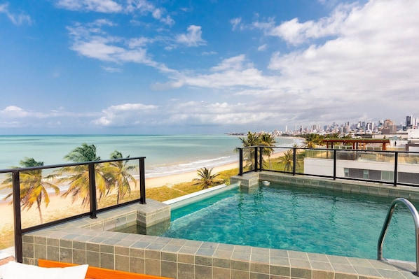 A pool with a view of the beach and city skyline.