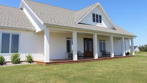 A single-story house with a covered porch, large windows, and a well-maintained lawn. - Water View Vacation Home Located in Rustico- Subdivision Access To Beach. (Rustico)