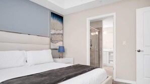 Un dormitorio con una cama grande, una mesita de noche, una lámpara y un cuadro en la pared.