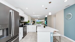 Una cocina moderna con armarios blancos, electrodomésticos de acero inoxidable y una isla central.