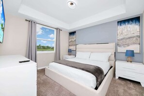 Ein Schlafzimmer mit einem großen Bett, einem Nachttisch, Vorhängen an einem Fenster und einem Gemälde an der Wand.