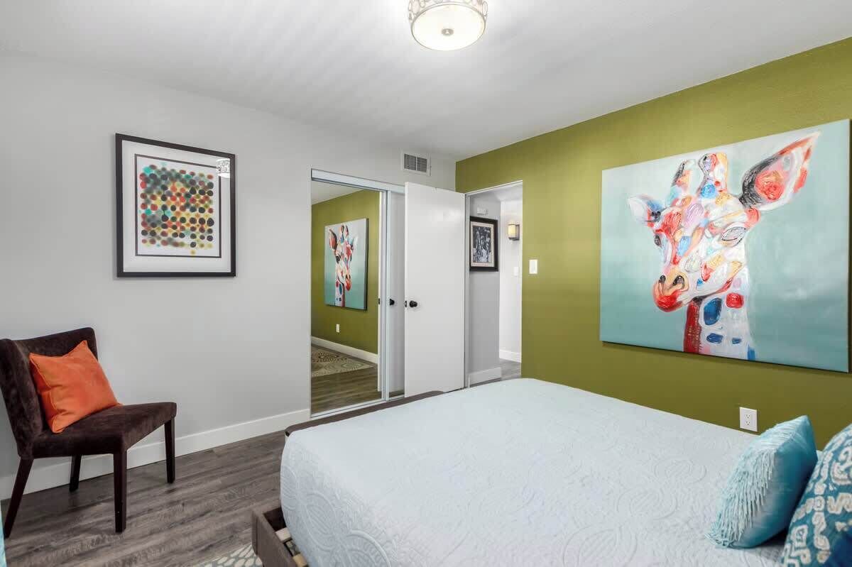 A bedroom with a bed, a chair, and artwork on the walls.