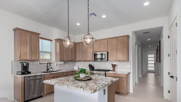 A modern kitchen with wooden cabinets, stainless steel appliances, and a central island. - Luxe 4BR Retreat w/ Pool, Hot Tub & Sunset Views (Goodyear)