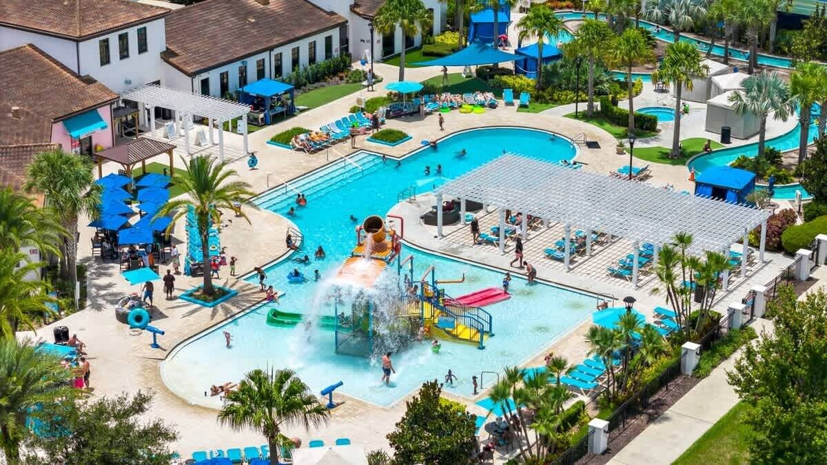 Ein großer Außenpool mit mehreren Bahnen, einer Wasserrutsche und einem Spielbereich für Kinder.