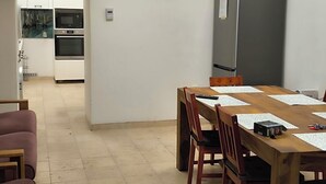 A compact kitchen with built-in appliances, a dining table with chairs, and a small seating area with a couch.
