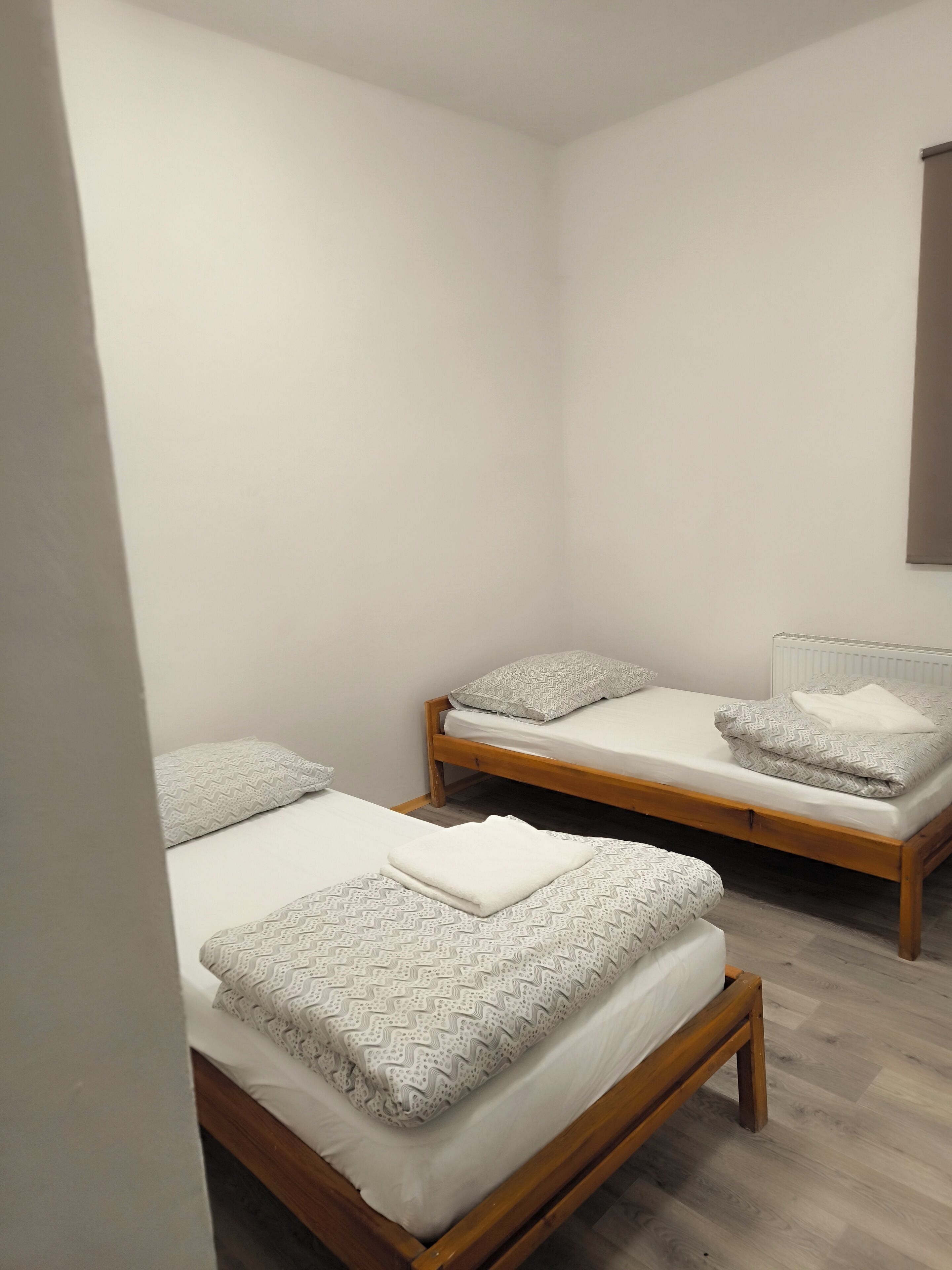 Una habitación pequeña y limpia con dos camas de madera, cada una con ropa de cama estampada y almohadas.