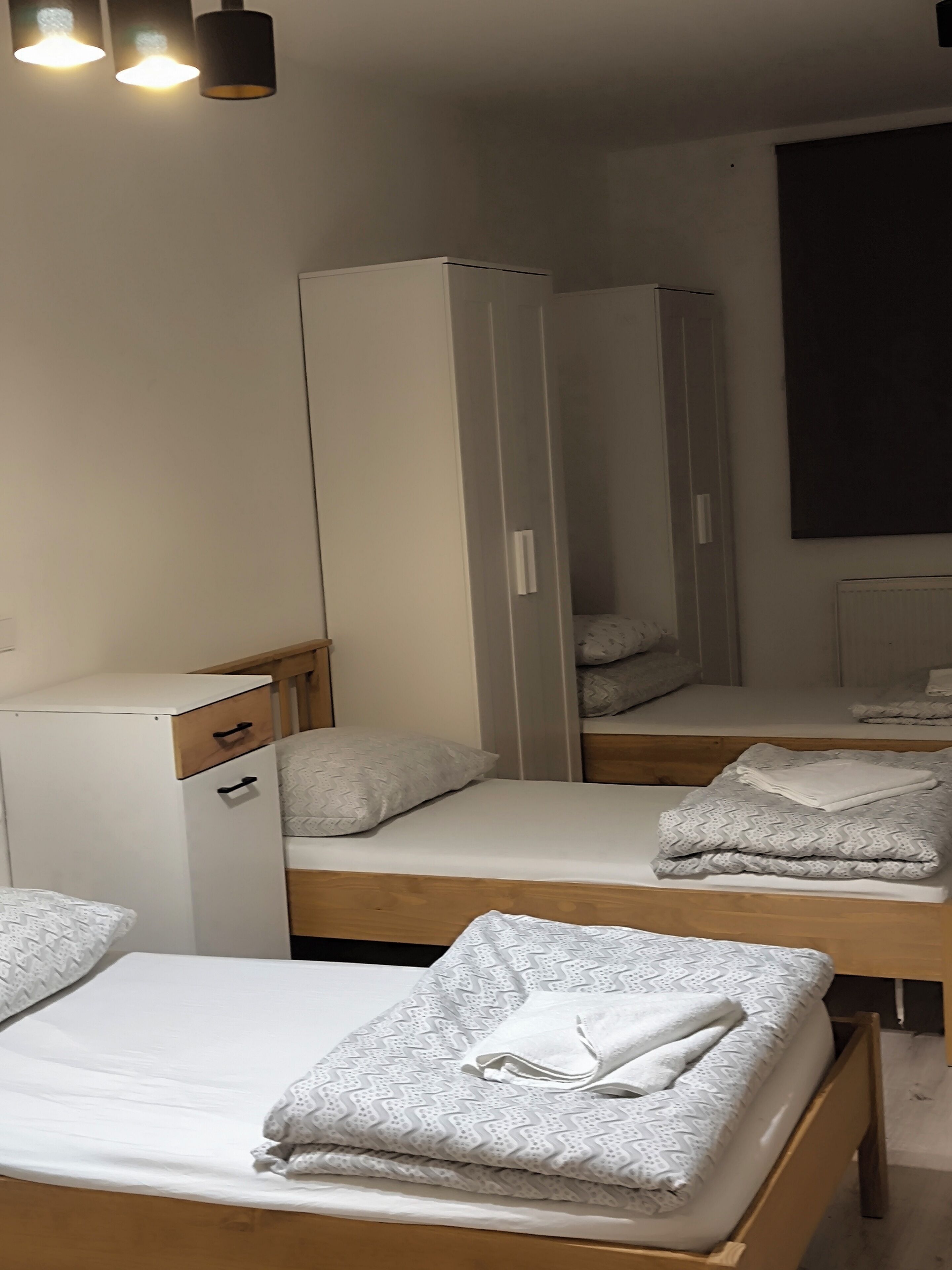 A hotel room with two beds, a wardrobe, and a mirror.
