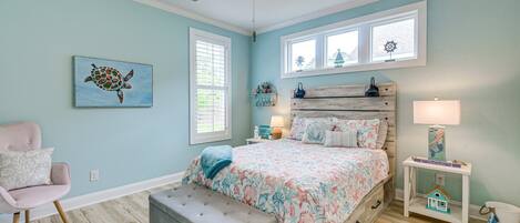 A bedroom with a bed, a chair, a nightstand, a lamp, and a ceiling fan.