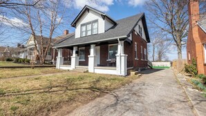 Ein zweistöckiges Haus mit Veranda, Backsteinfassade und Auffahrt zum Eingang.