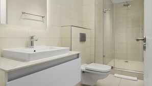 Une salle de bain moderne avec un lavabo blanc, des toilettes et une douche à parois de verre.