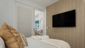 Une chambre d’hôtel moderne dotée d’un grand lit, d’un téléviseur à écran plat fixé au mur et d’un décor avec des panneaux en bois.