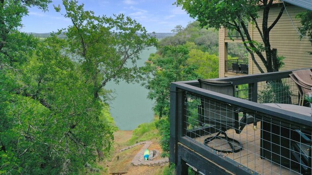 A balcony with a view of a lake and surrounding greenery.