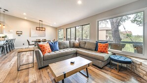 A modern living room with a sectional sofa, a coffee table, and a dining area with chairs and a table.