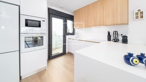 Une cuisine moderne avec des meubles blancs, un four encastré, un micro-ondes et un grand îlot central doté d’un évier.