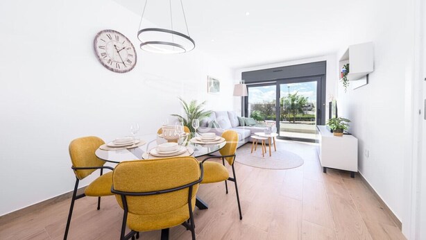 Un espace repas moderne avec une table ronde, des chaises jaunes et un design minimaliste.