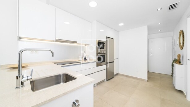 A modern kitchen with white cabinets, stainless steel appliances, and a large island with a sink. - Perla de Pilar - Private pool and rooftop near Beach - by Oyoostays (Pilar de la Horadada)