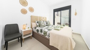 A modern bedroom with a bed, a chair, a bedside table, and a window. - Perla de Pilar - Private pool and rooftop near Beach - by Oyoostays (Pilar de la Horadada)