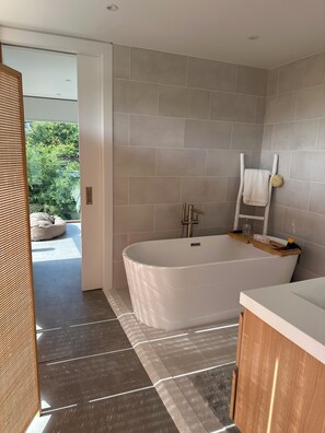 Une salle de bain moderne avec une baignoire sur pieds, un banc en bois et un porte-serviettes.
