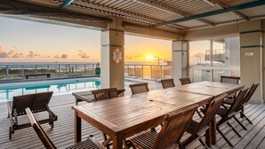Eine Holzterrasse mit Pool, Tisch und Stühlen.
