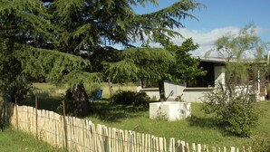 A fenced outdoor area with a building, trees, and a clear sky.