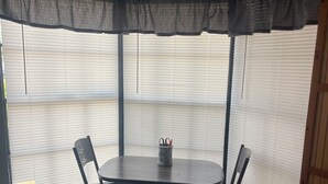 A corner dining area with a table and chairs, a window with blinds, and a mat on the floor. - Charming 2-bedroom house with WiFi, AC in fabulous Deltona , Florida (Deltona)