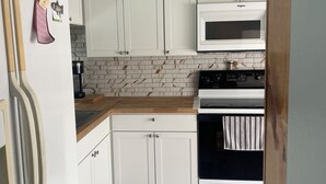 A compact kitchen with white cabinets, a built-in microwave, and an oven. - Charming 2-bedroom house with WiFi, AC in fabulous Deltona , Florida (Deltona)