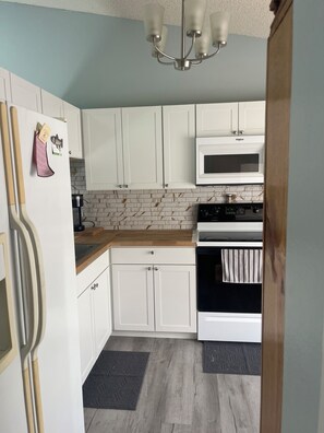 Een magnetron, een oven, een kookplaat, kookgerei, borden en bestek