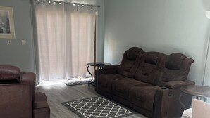 A living room with a brown sofa, a smaller couch, a coffee table, and a patterned rug. - Charming 2-bedroom house with WiFi, AC in fabulous Deltona , Florida (Deltona)