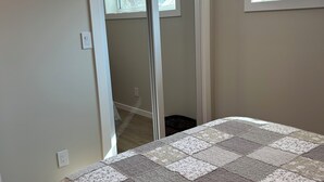 Un dormitorio con una cama grande, una puerta corredera que da a otra habitación y una ventana con vistas a árboles.