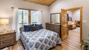 Quarto com cama, cómoda de madeira e ventoinha no teto.