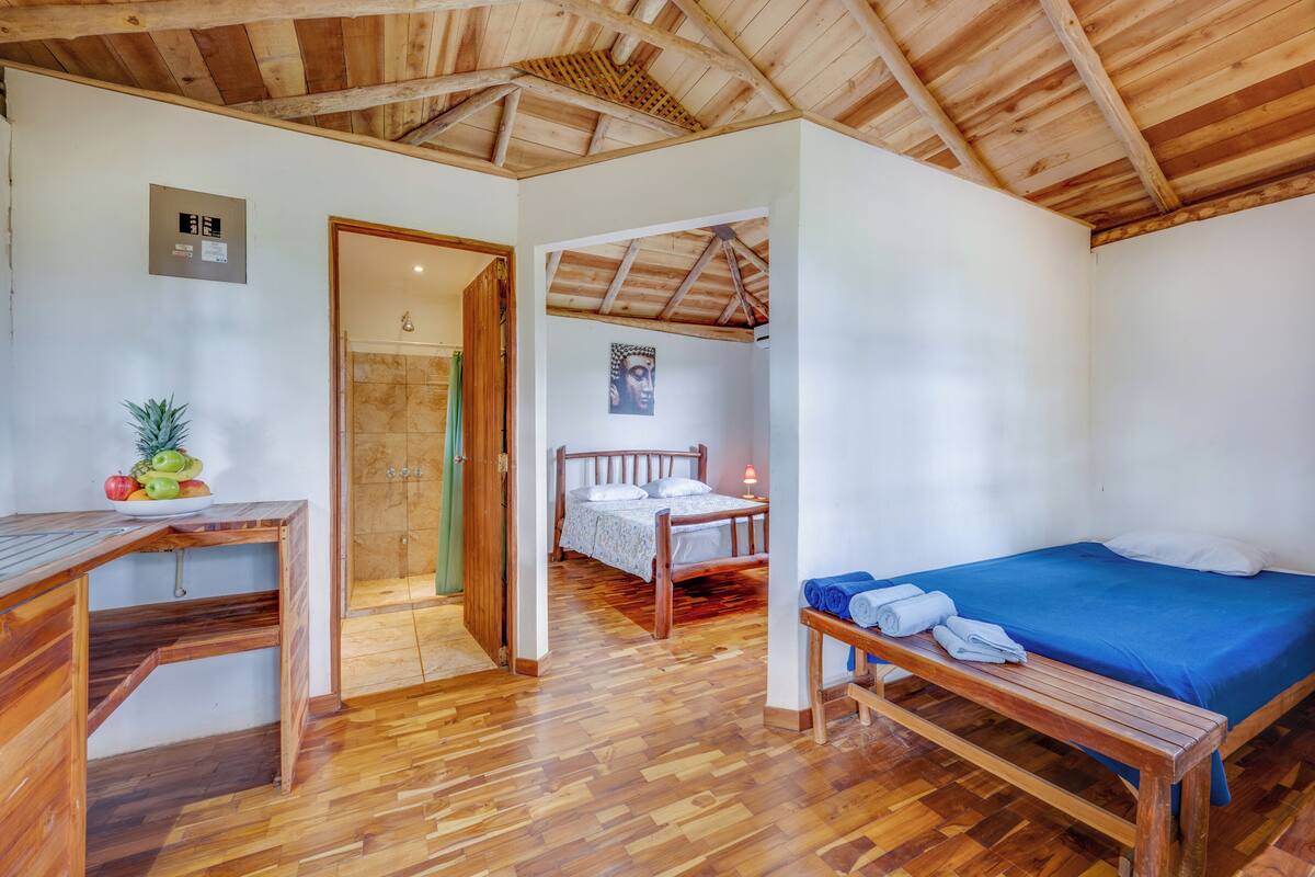 A wooden-framed room with a bed, a desk, and a bench.