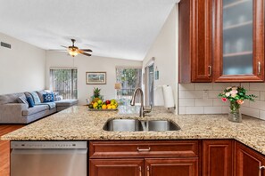 A kitchen with granite countertops, wooden cabinets, a stainless steel sink, and a dishwasher.