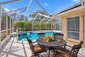 A covered outdoor area with a pool, a table with chairs, and a window.