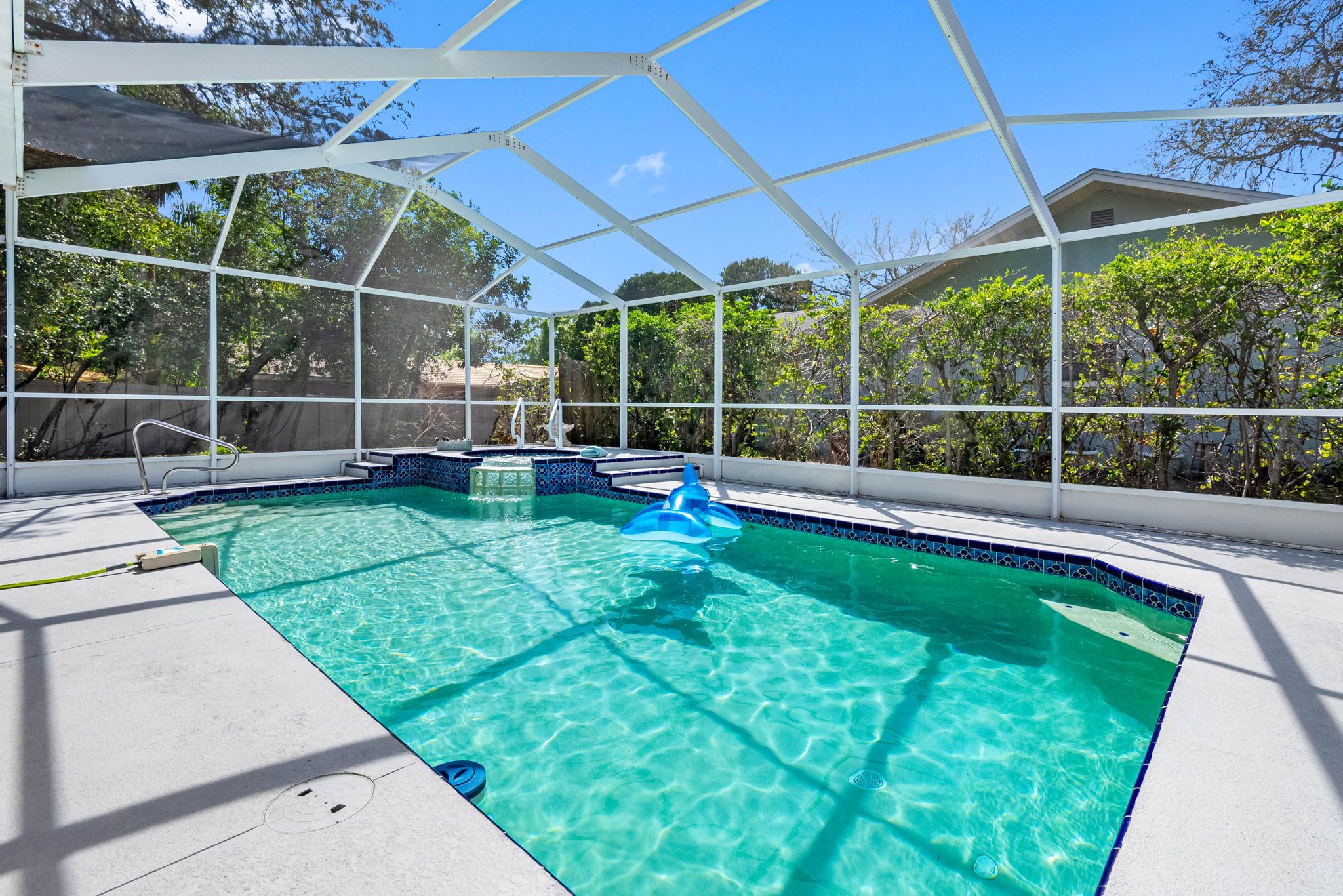 A clear blue pool with a white deck and a covered area with a white roof.