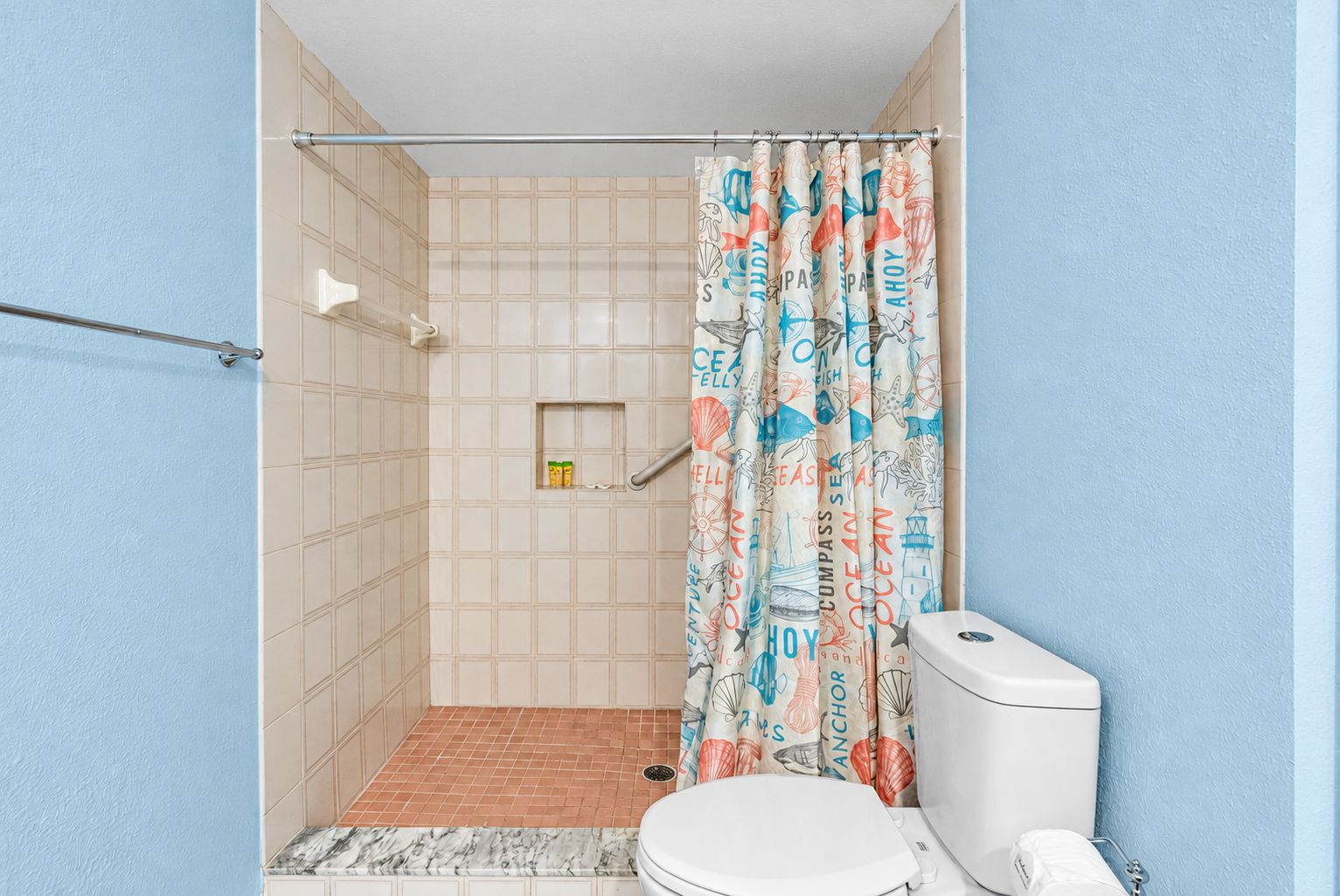 Un baño con ducha, inodoro y barra para toallas.