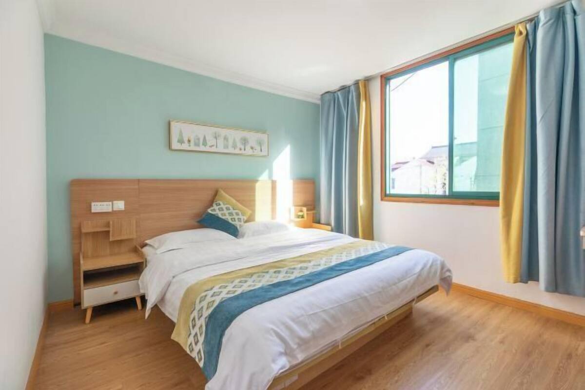 A bedroom with a wooden bed, a nightstand, a bedside table, and a window with curtains.