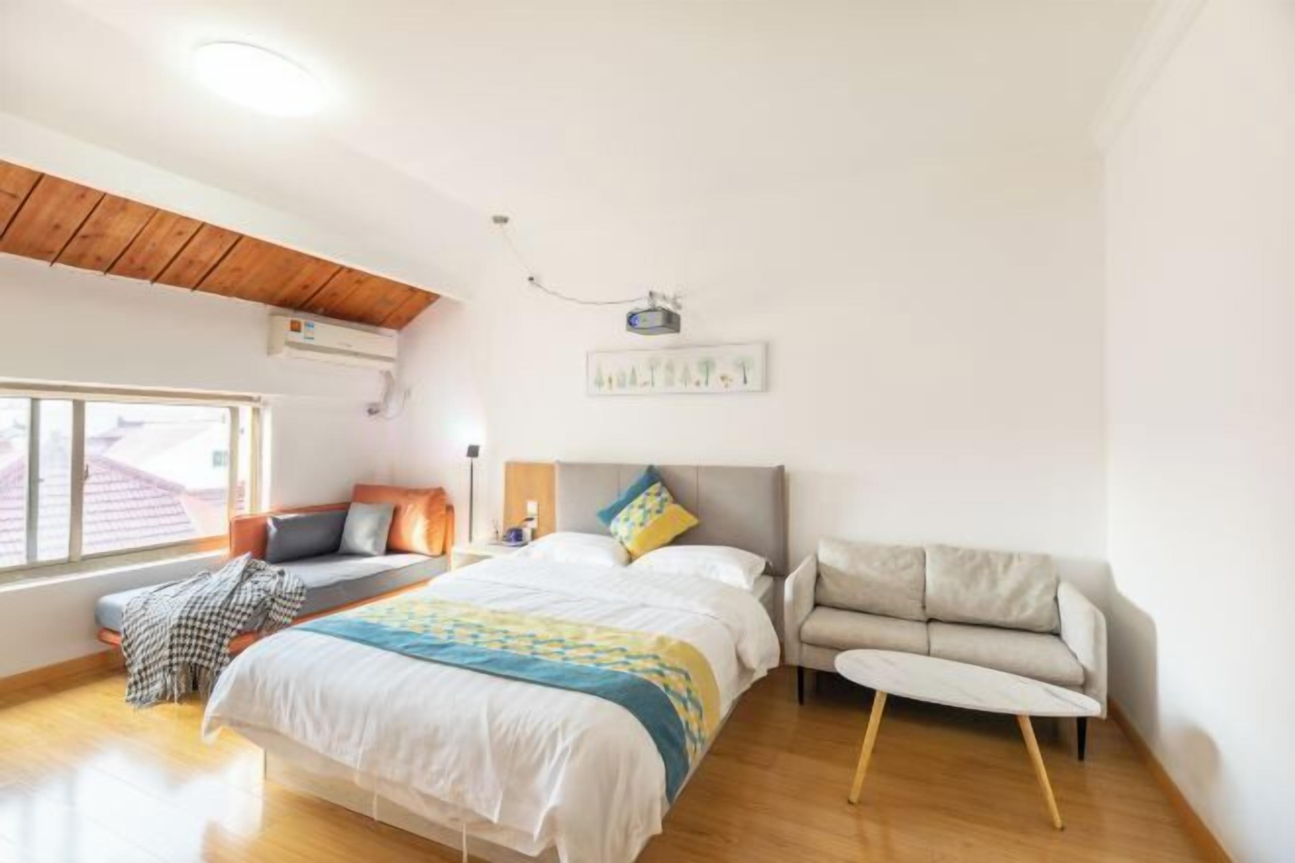A bedroom with a bed, a sofa, a window, and a ceiling fan.