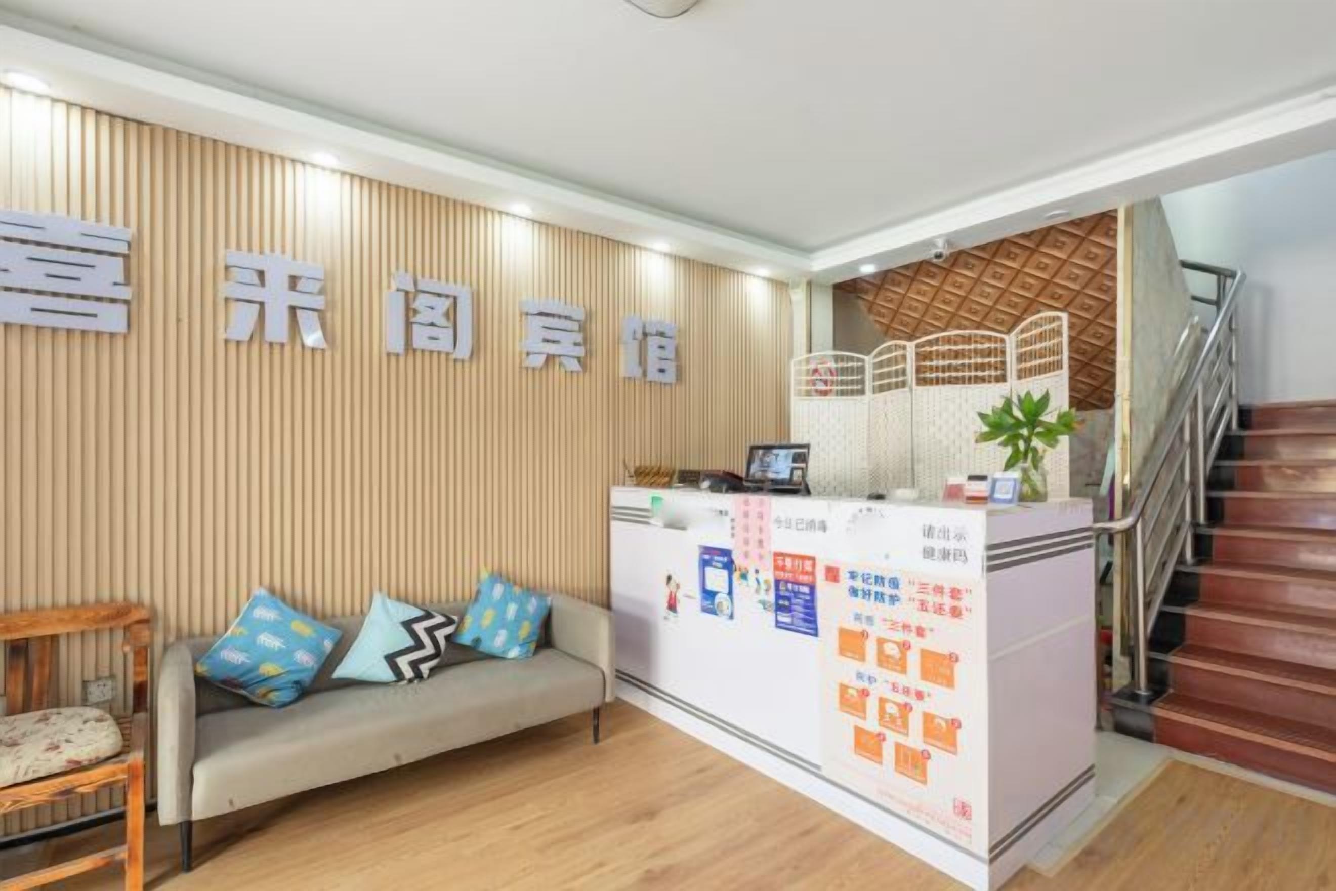 A reception area with a wooden panel wall, a reception desk, a sofa with cushions, and a staircase.