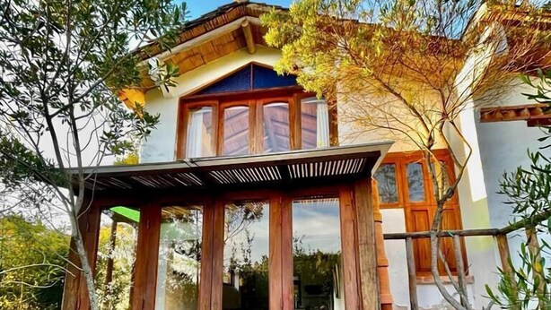 A two-story house with a stone foundation and a wooden porch. - Hostal Renacer  (Villa de Leyva)