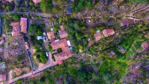An aerial view of a residential area with multiple houses, a road, and surrounding greenery. - Hostal Renacer  (Villa de Leyva)