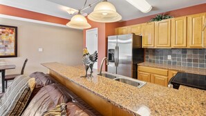 A kitchen with granite countertops, stainless steel appliances, and wooden cabinets. - Pigeon River View #204 (Sevierville)