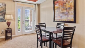 A dining area with a table and chairs, a lamp, and a painting on the wall. - Pigeon River View #204 (Sevierville)