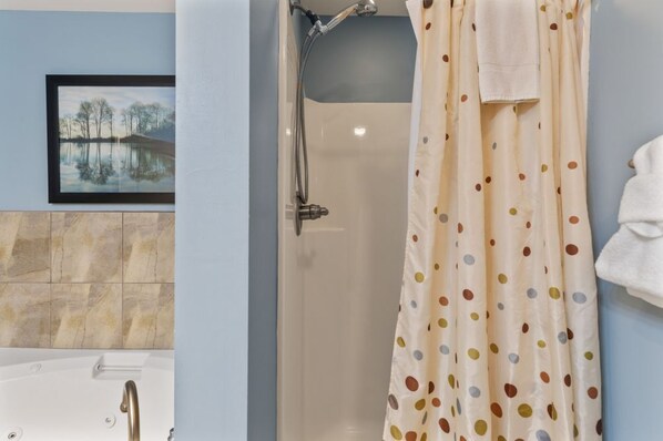 A bathroom with a bathtub, shower, and a polka-dotted curtain.