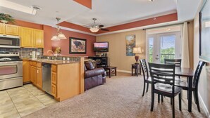 A modern kitchen with a central island, wooden cabinets, and stainless steel appliances. - Pigeon River View #204 (Sevierville)