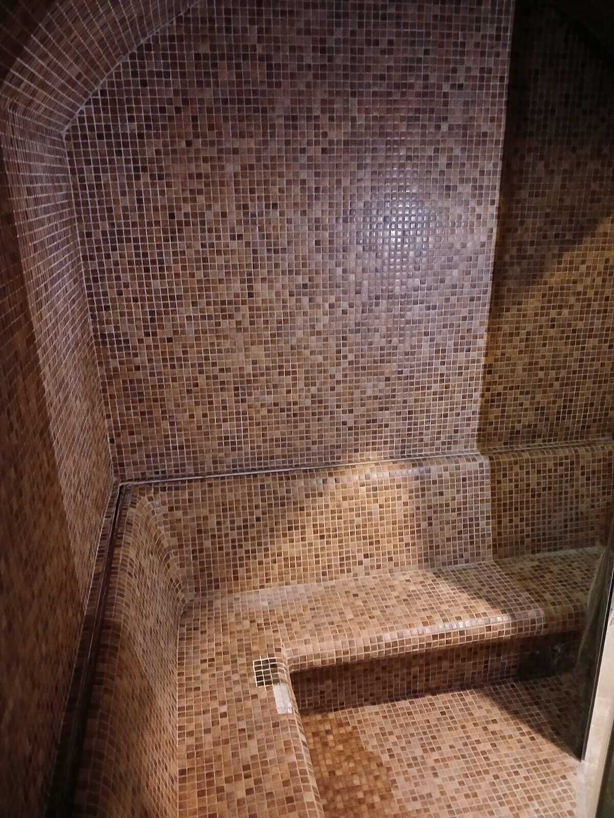 A tiled shower area with a curved design and a bench.