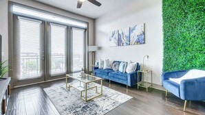 Ein modernes Wohnzimmer mit einem blauen Sofa, einem Glastisch und einer grünen Wand.