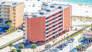 A multi-story hotel with a parking lot and beach view.
