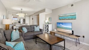 A living room with a sofa, coffee table, TV, and artwork on the wall.