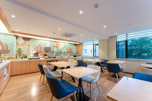 A modern dining area with a buffet, wooden flooring, and large windows.