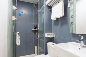 A modern bathroom with a glass-enclosed shower, a white sink, and a towel rack.
